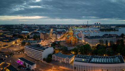 Lights from buildings and historic church in Helsinki harbor at dawn