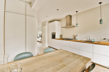 a kitchen and dining area in a house with white walls, wood flooring and an island table surrounded by blue chairs