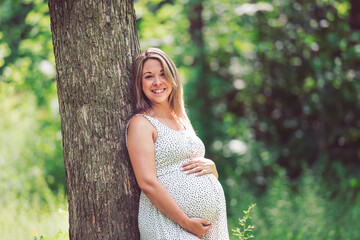 Pregnant woman posing in a green garden