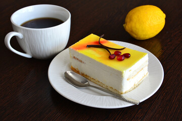 creamy cake with lemon jelly on the saucer with the cup of coffee 