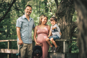 Family together in the summer park. Woman is pregnant