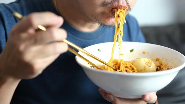 Asian men eating instant noodles with gusto
