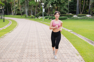 Woman jogger. back perspective portrait of young asian female wearing pink sportswear running in public park. Healthcare wellness concept.