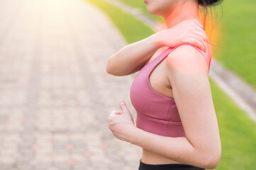 Woman jogger. young 30s asian female wearing pink sportswear holding her back pain after running...
