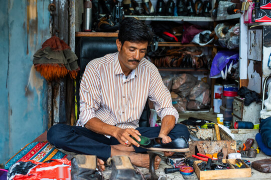 Indian man repairs shoes on the street also called shoemaker, cobbler or mochi
