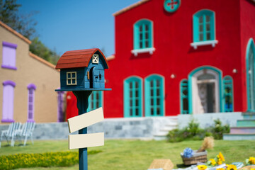Colorful home mailbox in garden. Wooden box for mail in the yard against colorful houses, letterbox, house shape mailbox. have a mail in your mailbox house.