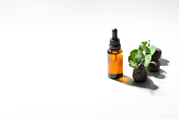 Brown glass dropper bottle  on white  isolated background witrh stones and green plant. Natural  skin care concept. .