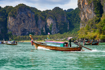 Traditional Thai longtail boat navigating in the Andaman Sea in front of Railay West Beach on the Railay Peninsula in the Province of Krabi, Thailand, Southeast Asia