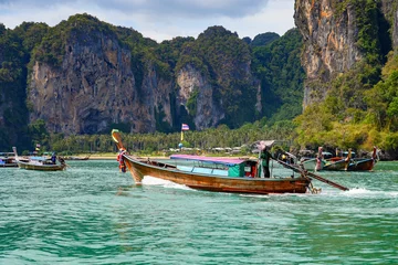 Foto auf Acrylglas Railay Strand, Krabi, Thailand Traditional Thai longtail boat navigating in the Andaman Sea in front of Railay West Beach on the Railay Peninsula in the Province of Krabi, Thailand, Southeast Asia