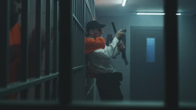 Male prisoner strangles prison officer, takes keys, opens prison cell. Criminal in orange uniform escapes from jail or detention center. Cinematic scene playback for action movie. Film production.