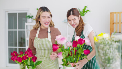 Two asian woman florist working in flower shop. Two woman florist helping together choosing and arrangements rose flowers in vase for selling at flower shop. Florist concept, Small business owner