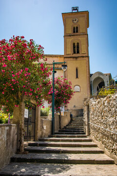 Up top of the cobblestone stairs, high on the hill sits The Bell Tower of Ravello, Italy on the Amalfi Coast. Beautiful flowers line the walkway leading up to the ancient church.