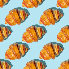 Seamless pattern with sweet croissant on blue background.