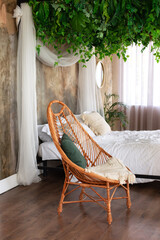 Interior boho design bedroom with garland flowers and plants. Cozy light bedroom in Scandinavian style bedroom, canopy bed and wicker rattan armchair. Bed decorated flowing white curtains canopies.   © stock_studio