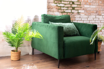 Elegant living room interior in loft style with green armchair near brick wall in room. Interior...