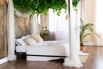 Cozy light bedroom in Scandinavian style bedroom, canopy bed, plant in pot. Bed decorated flowing...