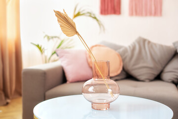 Minimal Scandinavian cozy style decor. Template. Cozy grey sofa and coffee table with bouquet of dried flowers in living room. Branch dried plant in glass vase on a table. Home interior decor.  © stock_studio
