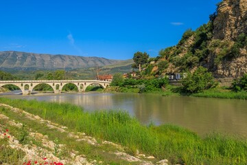 Gorica Bridge of Berat spans over Osum River, connecting ancient neighborhoods of Berat city in Albania. its stone arches and historic charm, Gorica Bridge in Berat is a picturesque symbol of the town