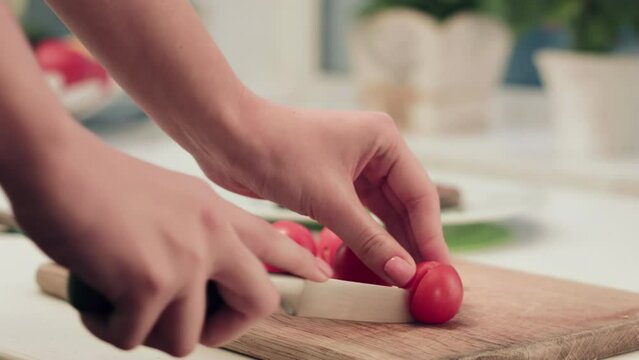 Culinary mastery as a woman expertly slices mini tomatoes with a sharp knife, creating a vibrant and flavorful dish.
