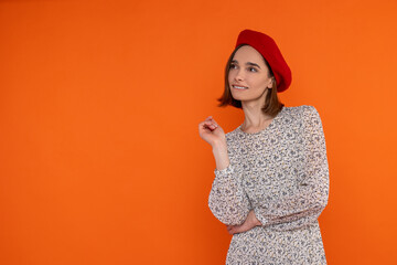 Dreaming adult woman wearing elegant dress and red beret looking away empty space fir advertisement - obrazy, fototapety, plakaty