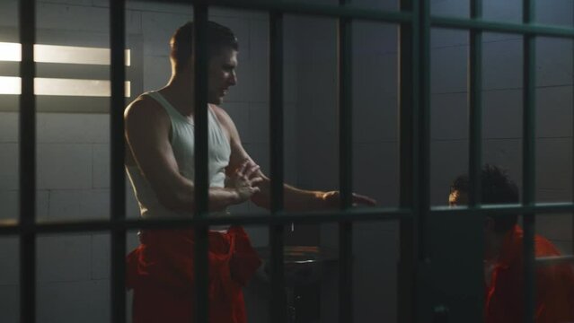 Male prisoners fight in prison cell Aggressive criminals in orange uniforms hit each other in jail Detention center or correctional facility Montage cinematic fighting scene playback for action movie.