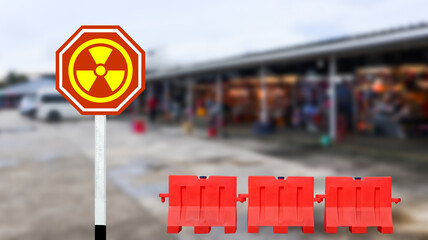 Red sign with graphic of radioactive turbine due to radiation materials on blurred building background                               
