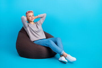 Portrait of good mood lovely girl wear gray clothes lay on bean bag eyes closed arms behind head...