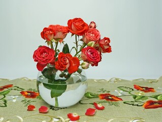 Bouquet of red roses in a glass round vase on a colorful napkin