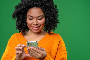 Curly-haired young woman in orange with a smartphone in hands
