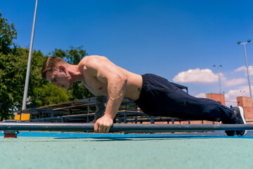 young pumped-up athlete doing push-ups from the ground during street training endurance exercise swings arms and shoulders