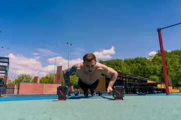 young pumped-up athlete doing push-ups from the ground during street training endurance exercise swings arms and shoulders
