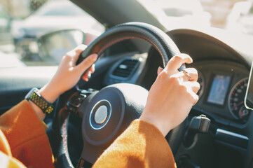 Side view of a woman driving a car and keeping both hands on the steering wheel on her way to work