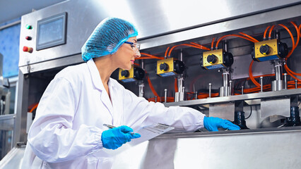 Bottling factory worker inspecting quality of water bottles before shipment. Reverse osmosis system...