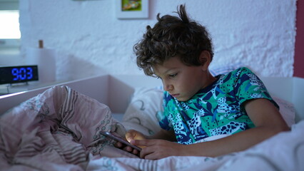 Child browsing internet online lying in bed in the morning looking at screen