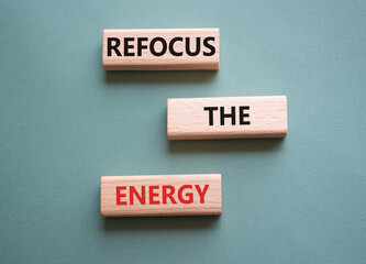 Refocus the Energy symbol. Concept word Refocus the Energy on wooden blocks. Beautiful grey green background. Business and Refocus the Energy concept. Copy space