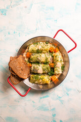 top view cabbage rolls in metal dishes on a blue background.