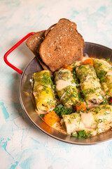 top view cabbage rolls in metal dishes on a blue background.