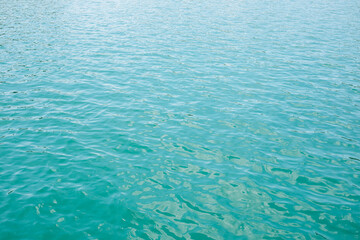 Abstract nature textured background, water waves in the lake with sun reflection, clear blue-green water