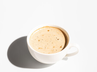 Side view of White Cup of cappuccino with creamy foam on white background. Copy space. Hard light