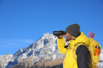 Tourist with backpack and binoculars in mountains