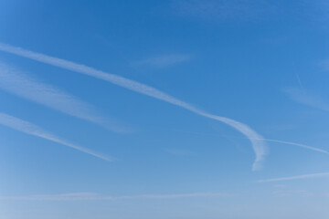 blue sky with a few clouds and airplane trails