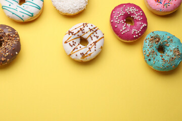 Fototapeta na wymiar Tasty glazed donuts on yellow background, flat lay. Space for text