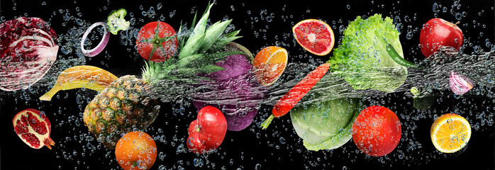Many fruits and vegetables falling into water against black background