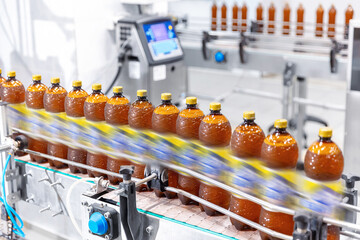 Brown plastic beer drink alcohol bottles move on brewery conveyor, modern production line. Motion blur effect