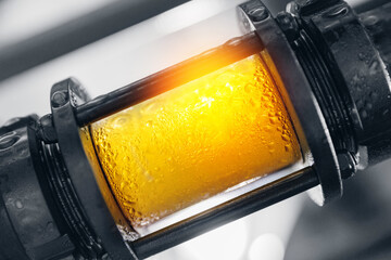 Brewing equipment for quality control, sight glass full of golden beer on stainless steel pipe....