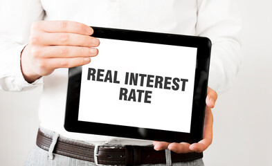 Text REAL INTEREST RATE on tablet display in businessman hands on the white background. Business concept