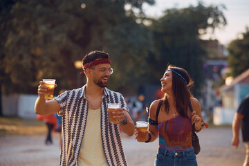 Young happy couple drinks beer while going to music concert.