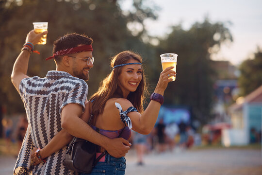 Happy woman and her boyfriend drink beer on music festival.
