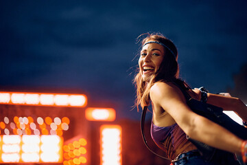Cheerful woman in front of music stage during summer festival looking at camera.