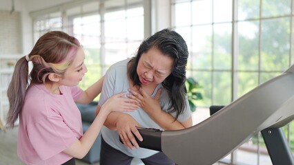 Fototapeta premium Asian elderly women have chest pain while exercising on the machine. Young women take care her mother having chest pain while exercising. Health care concept